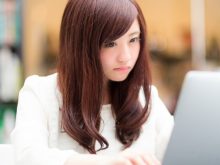PCを見て悩む女性